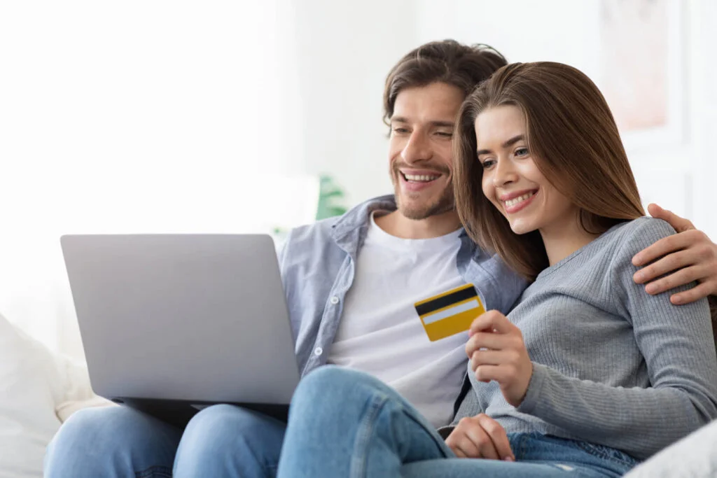 Couple sitting on a couch and making online transaction through laptop