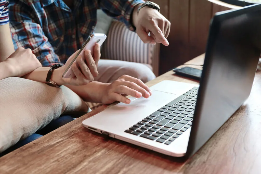 Persons sitting by the laptop